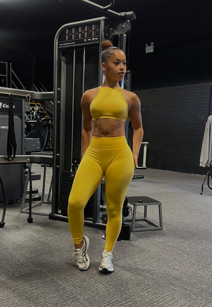 Coach is posing in the gym ina. yellow workout outfit.